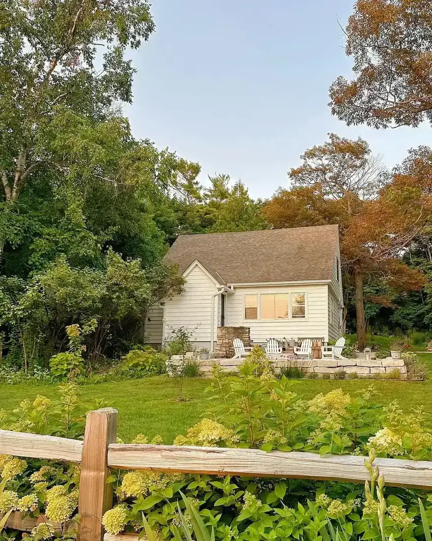 Cream stone cottage with paved terrace and meadow lawn stretching behind