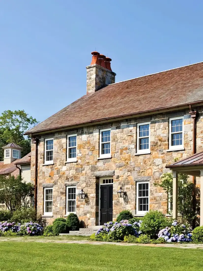 Stone farmhouse exterior with hydrangeas along the front wall