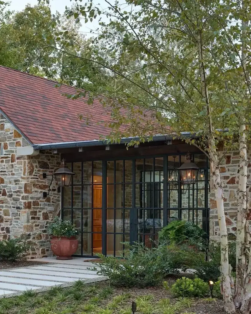 Stone house with black steel windows and warm terracotta roof