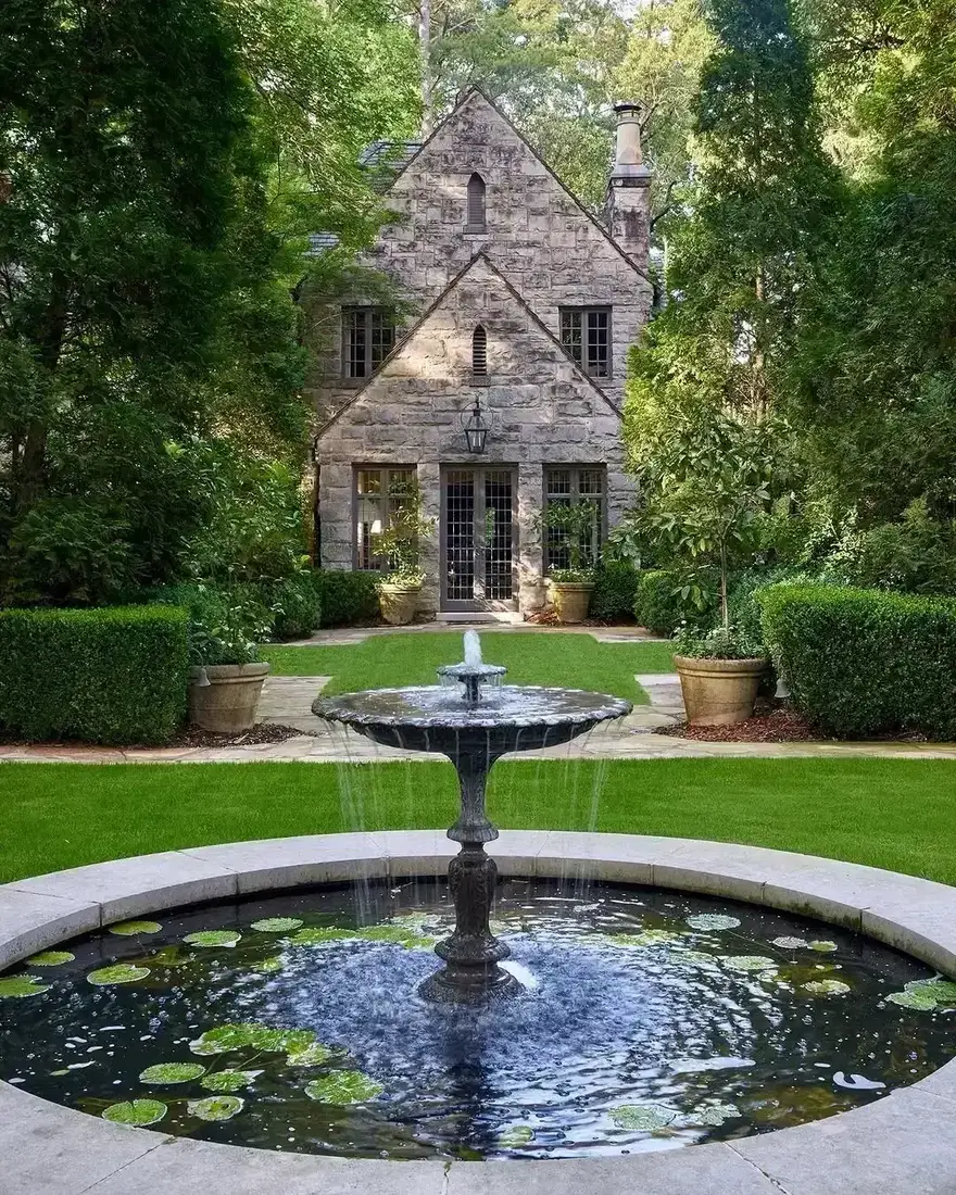 Stone Tudor house with fountain in clipped formal garden