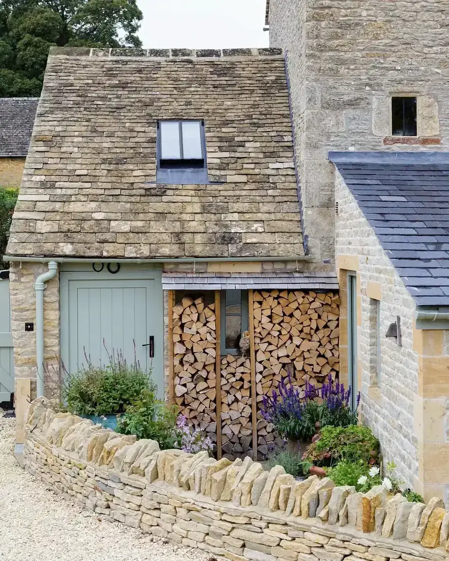 Stone cottage with turquoise painted shutters flanking a rounded arched front door