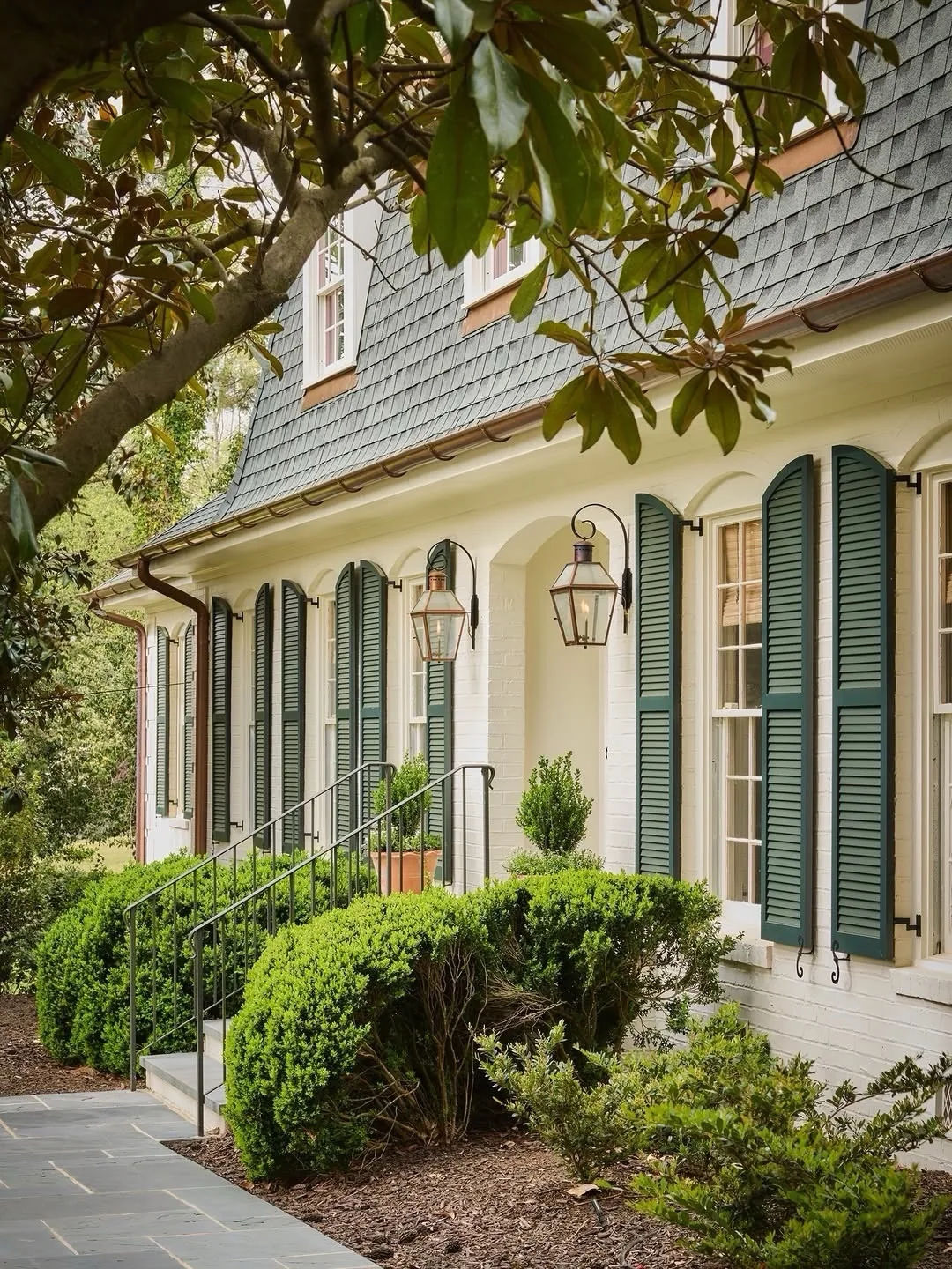 Cream stucco house with green louvered shutters
