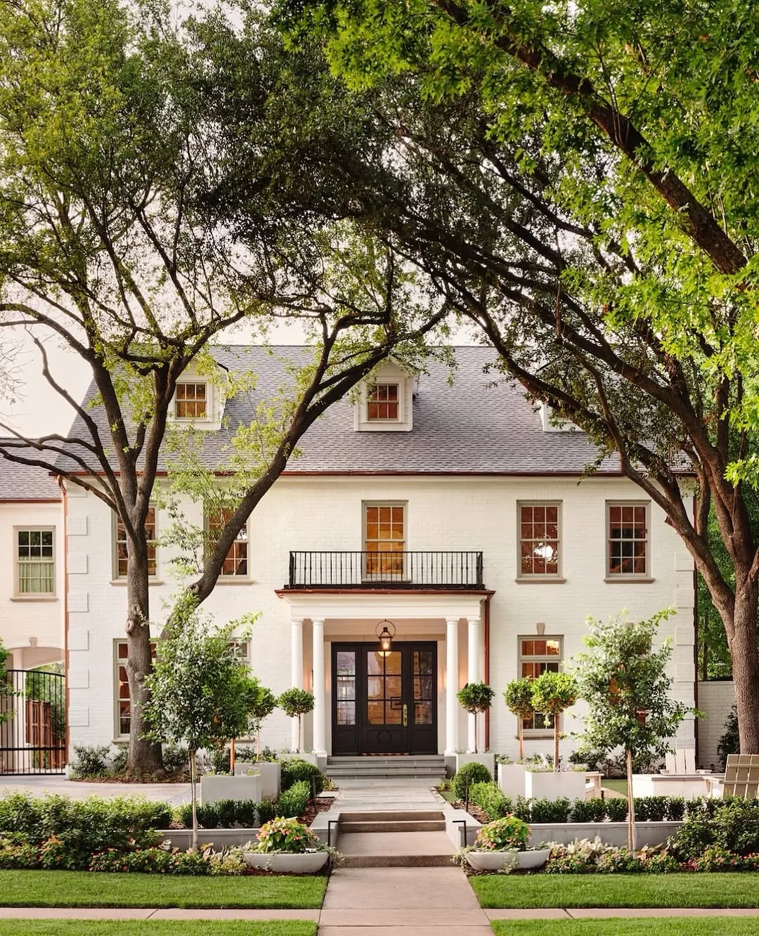 Cream stucco house with oak trees and a portico