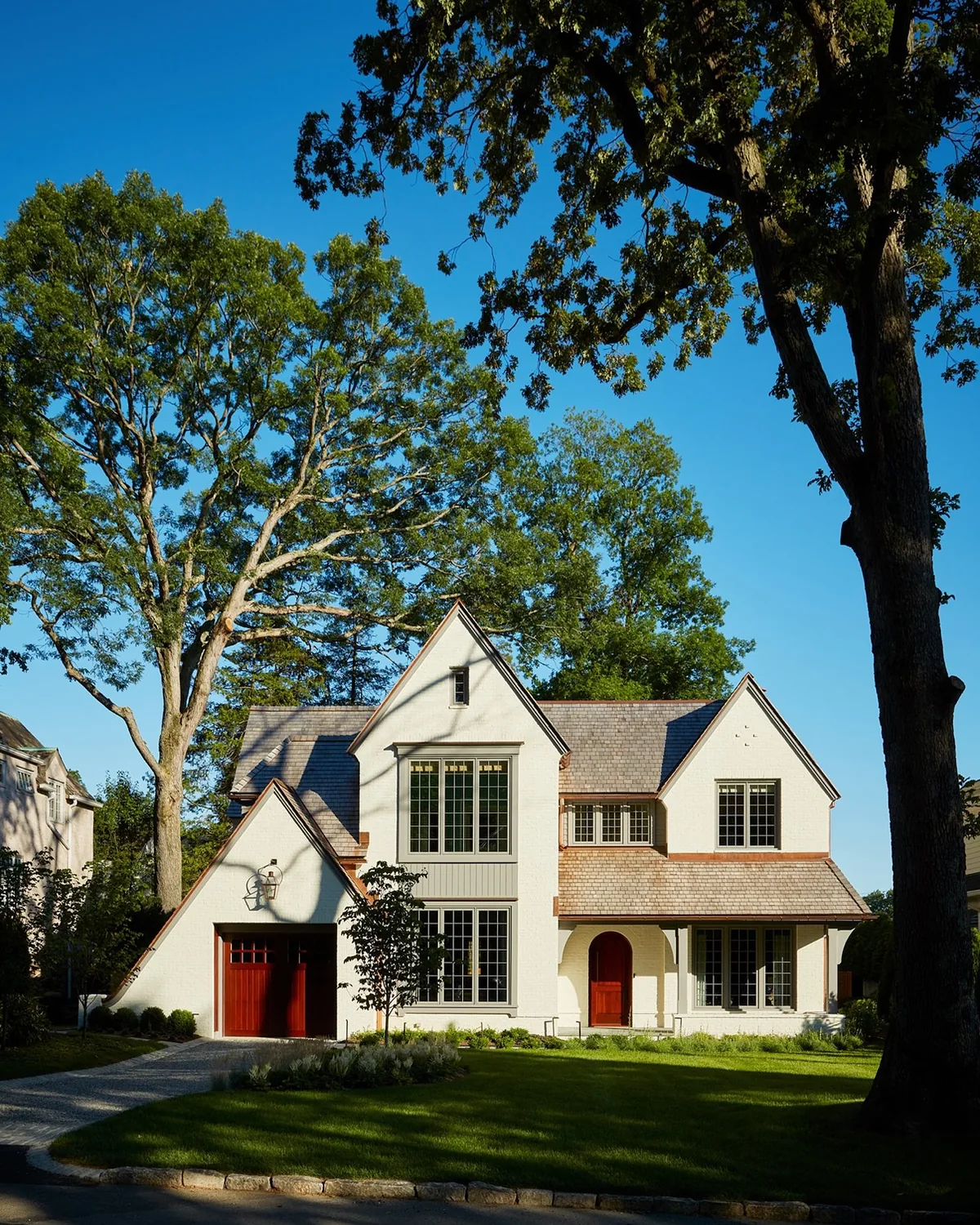Cream Tudor stucco house with red garage doors