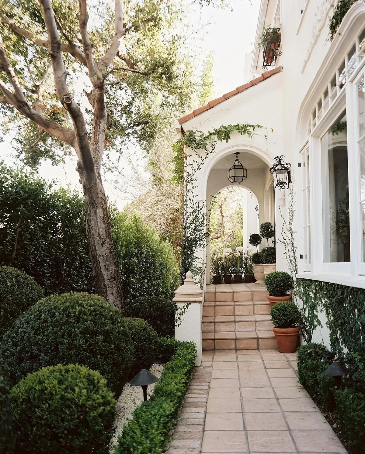 Spanish white stucco arched entry with boxwood