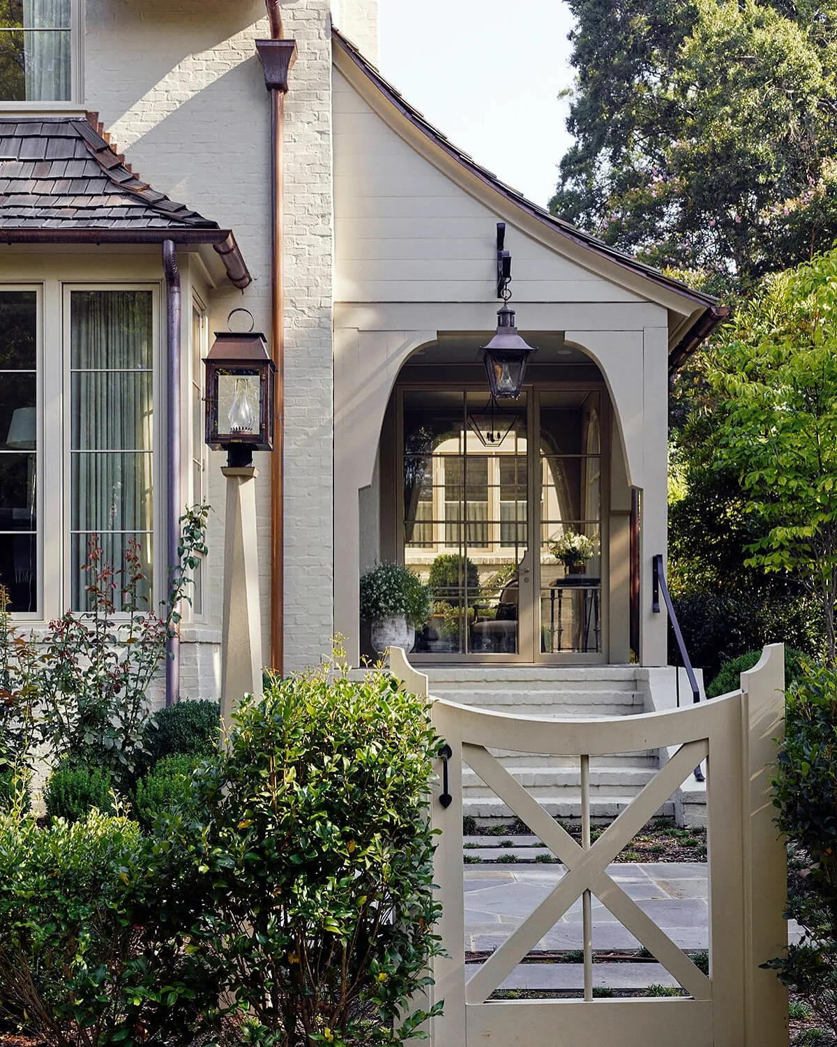 White stucco cottage with an arched porch and lanterns