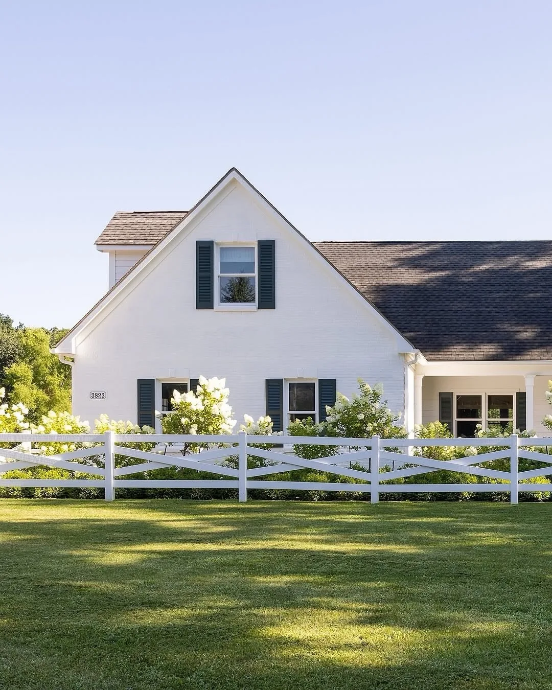 White stucco cottage with black shutters and a picket fence