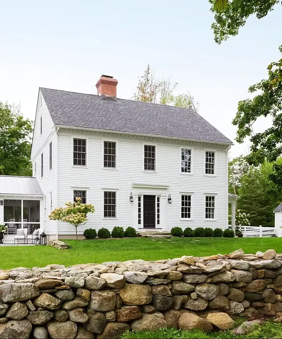 White colonial farmhouse with stone wall