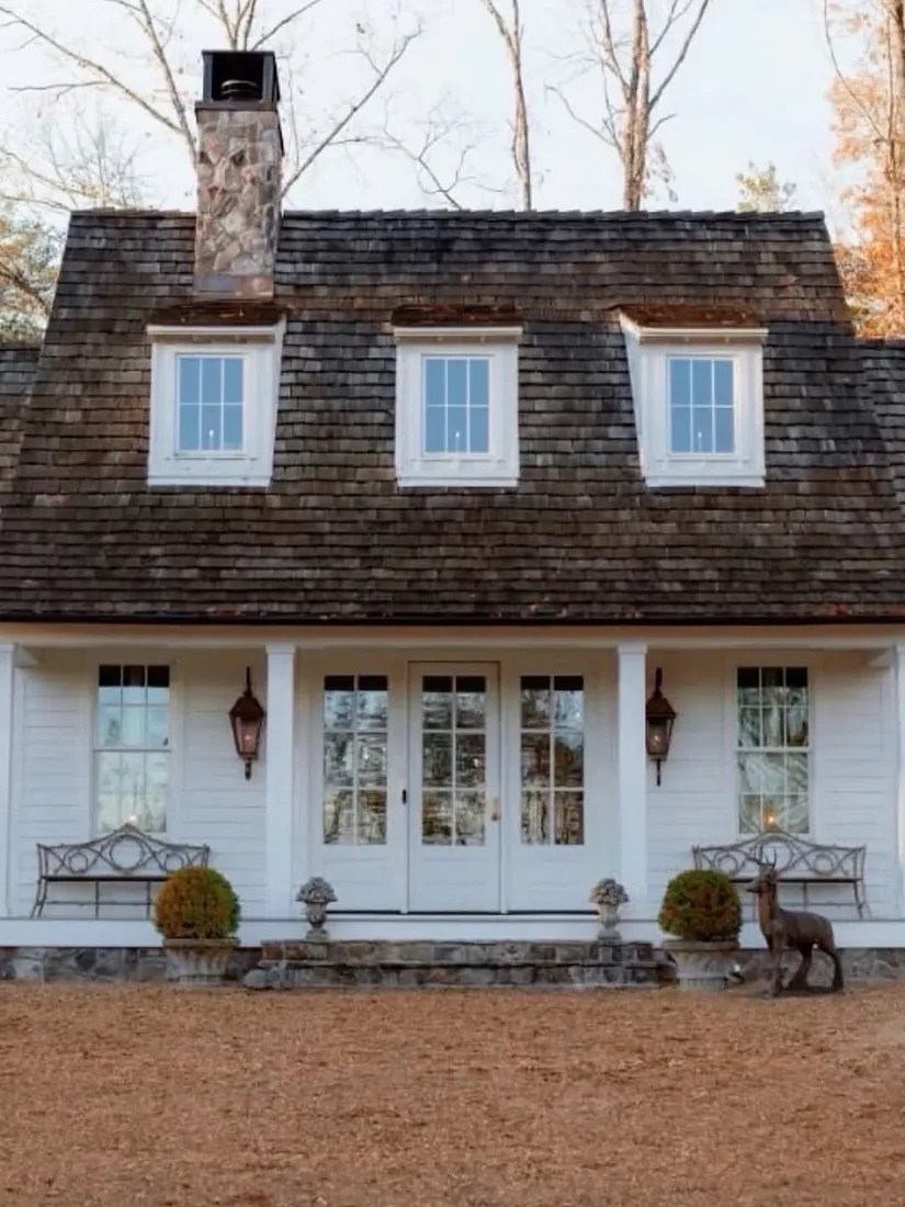 Small white cottage farmhouse with tidy porch and green lawn showing curb appeal