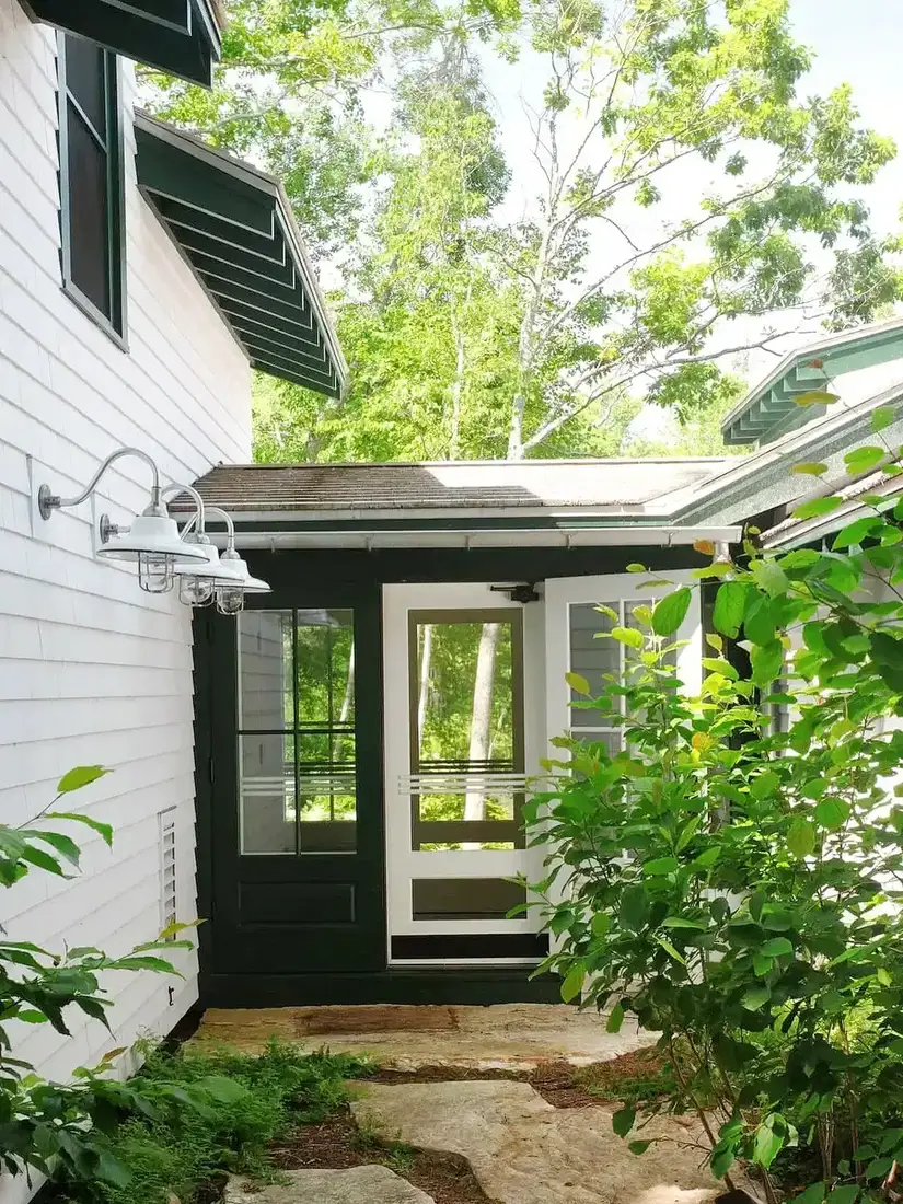 Deep green entry porch on white farmhouse adding contrast and shade