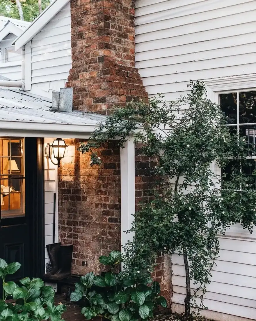 White farmhouse with tall brick chimney and wide sloping lawn