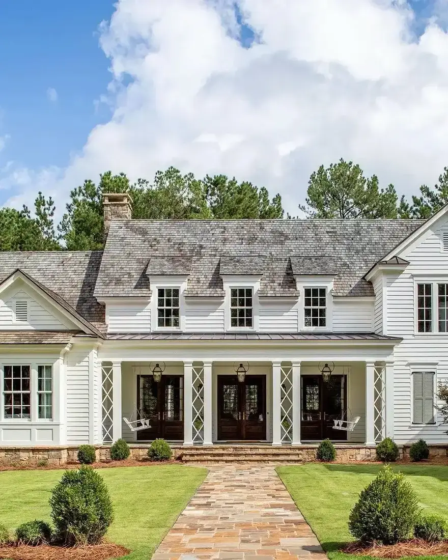 White farmhouse with a weathered cedar shingle roof and a flagstone path leading to the front steps