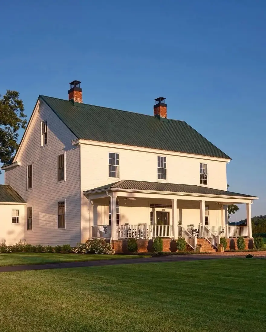 White farmhouse exterior with deep front porch and white columns in daylight