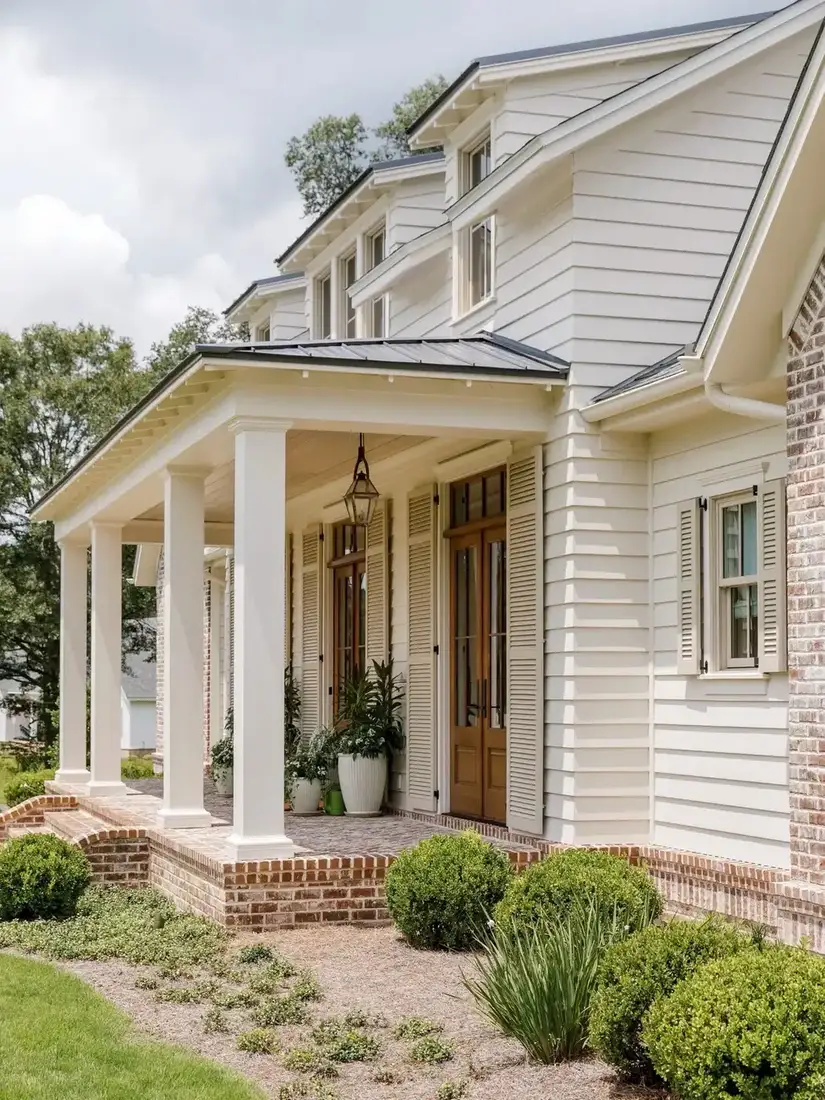 White farmhouse with covered front porch and dark roof and paneled front door