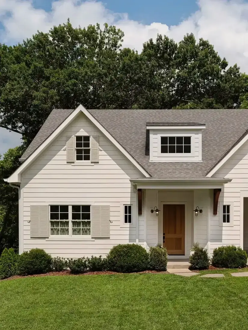 White farmhouse exterior with warm wood front door and white trim
