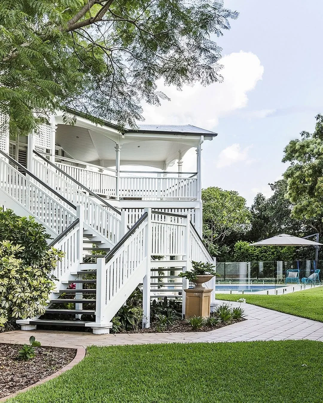 Queenslander house with white stairs and a pool