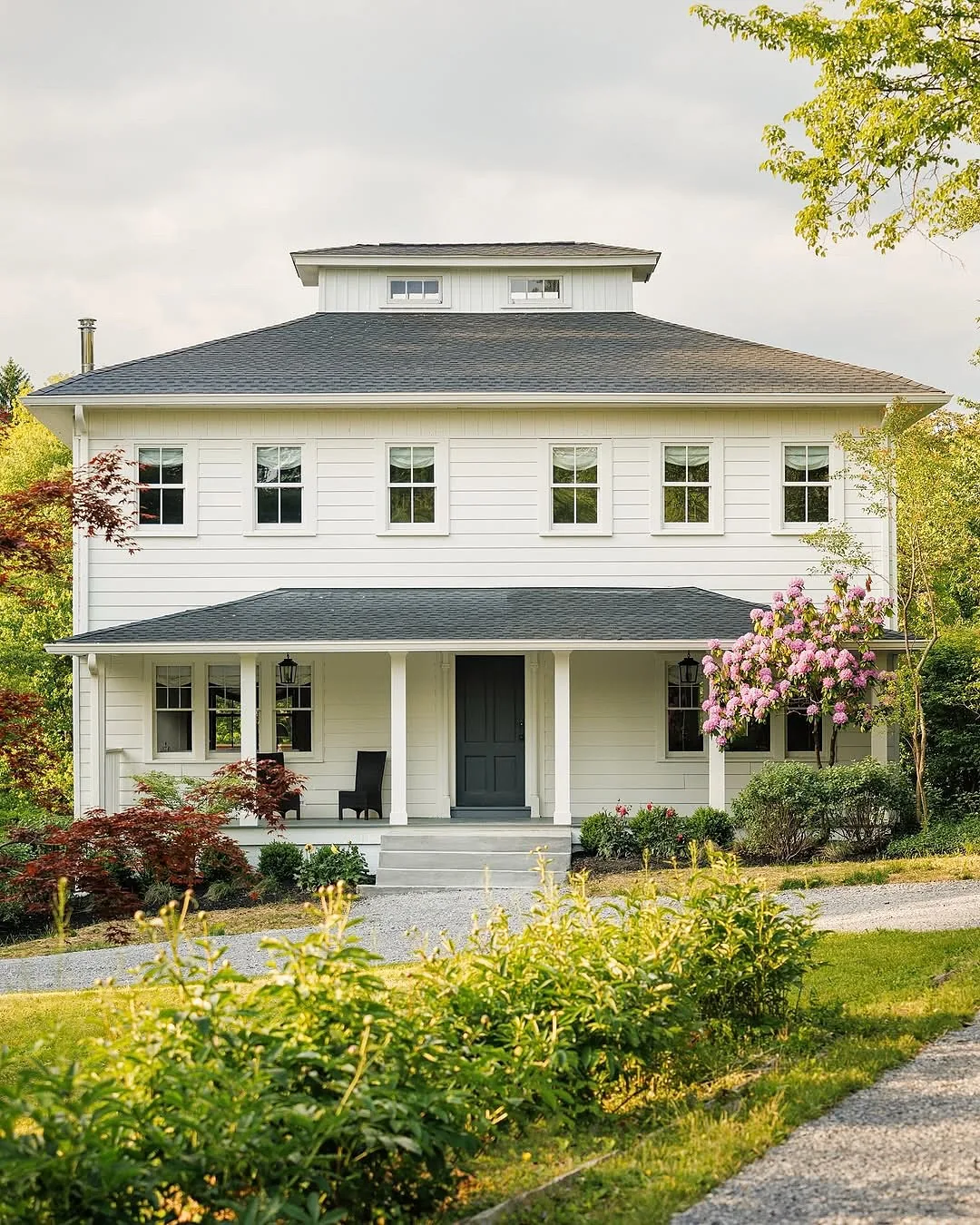 White foursquare house with a hip roof and porch
