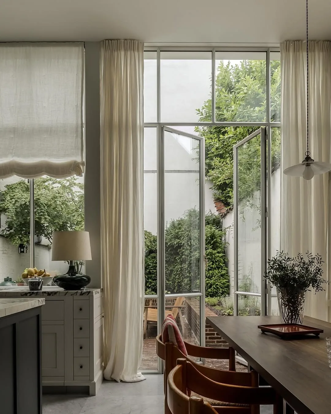 Garden room kitchen with tall windows and linen curtains