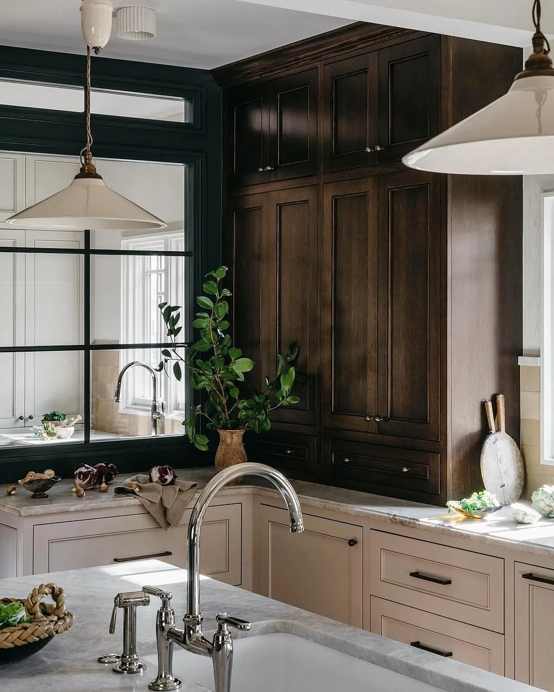 Dark wood cabinets in a cream kitchen with a marble sink