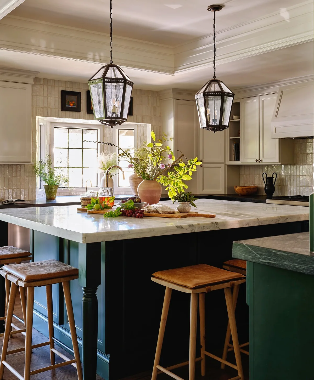 Dark green island in a cream kitchen with lanterns