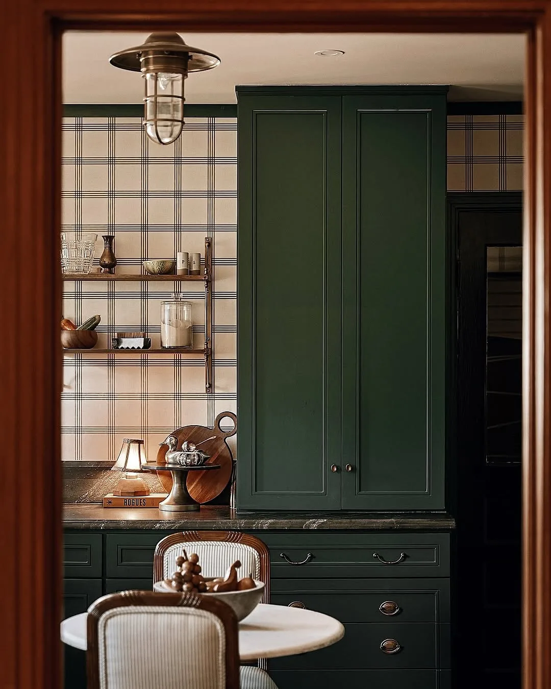 Dark green kitchen cabinets with plaid wallpaper