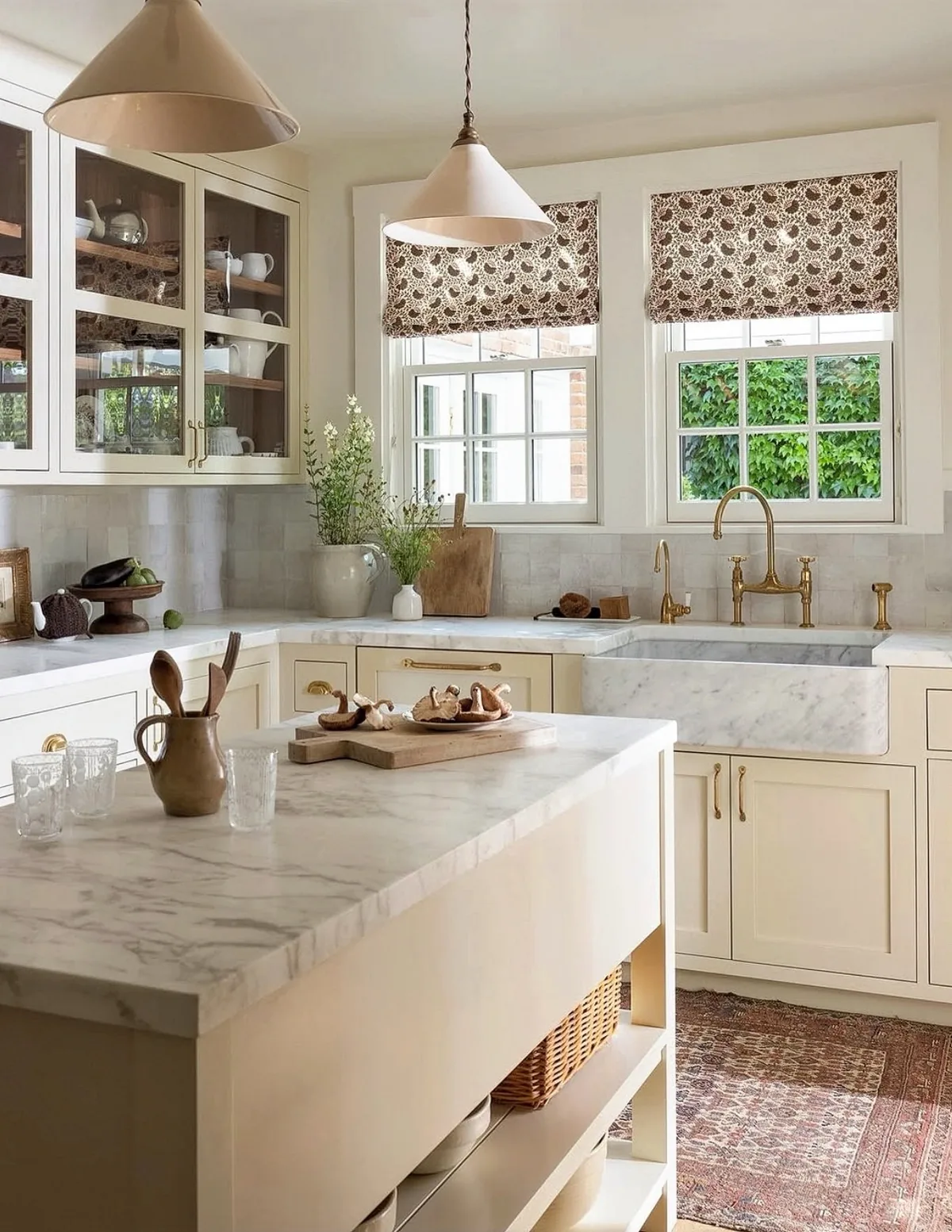 Cream kitchen with a marble island and brass faucet