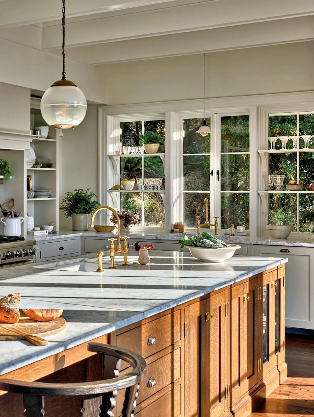 Oak island in a white kitchen with a garden window and brass