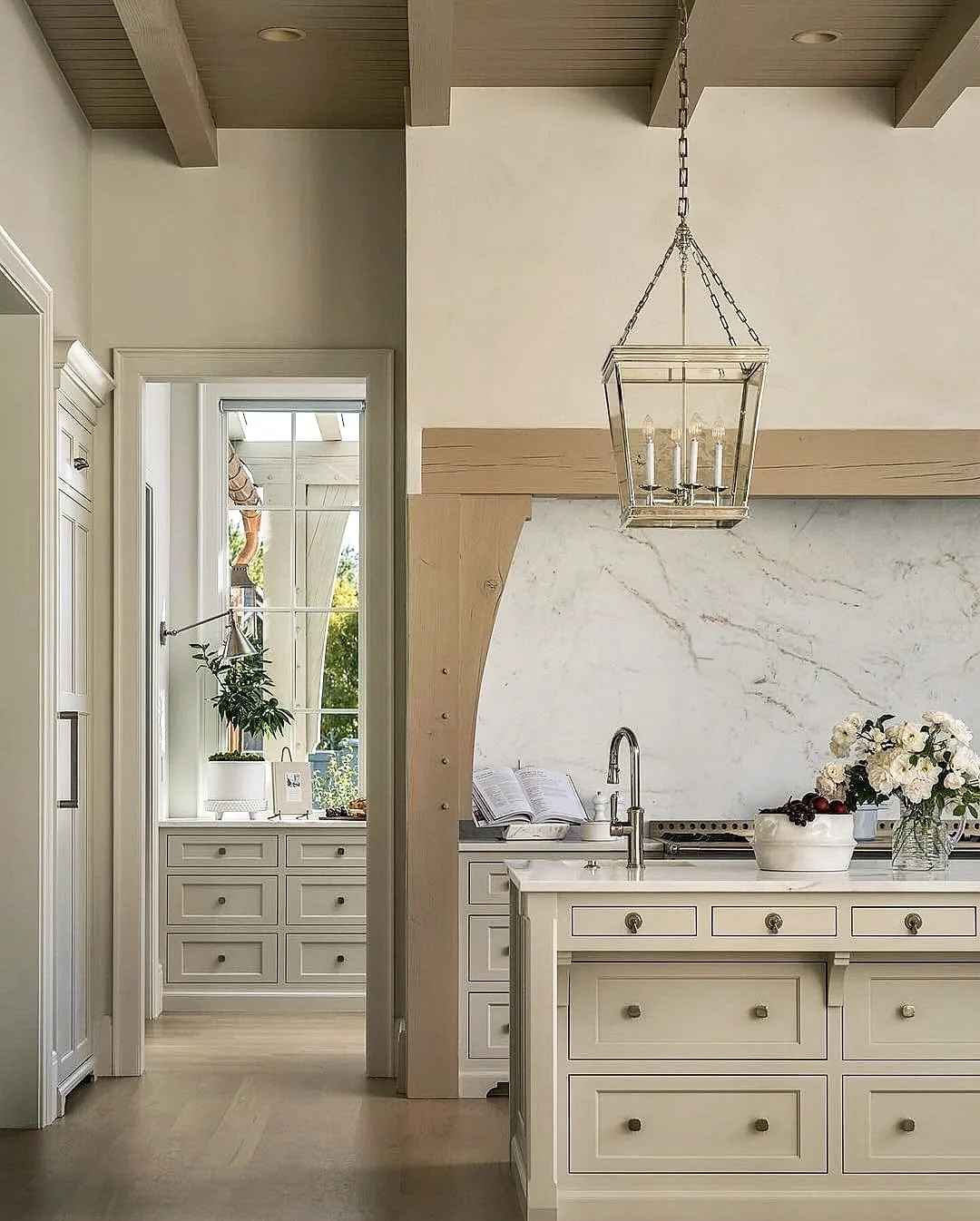 Cream kitchen with a marble slab hood and lantern