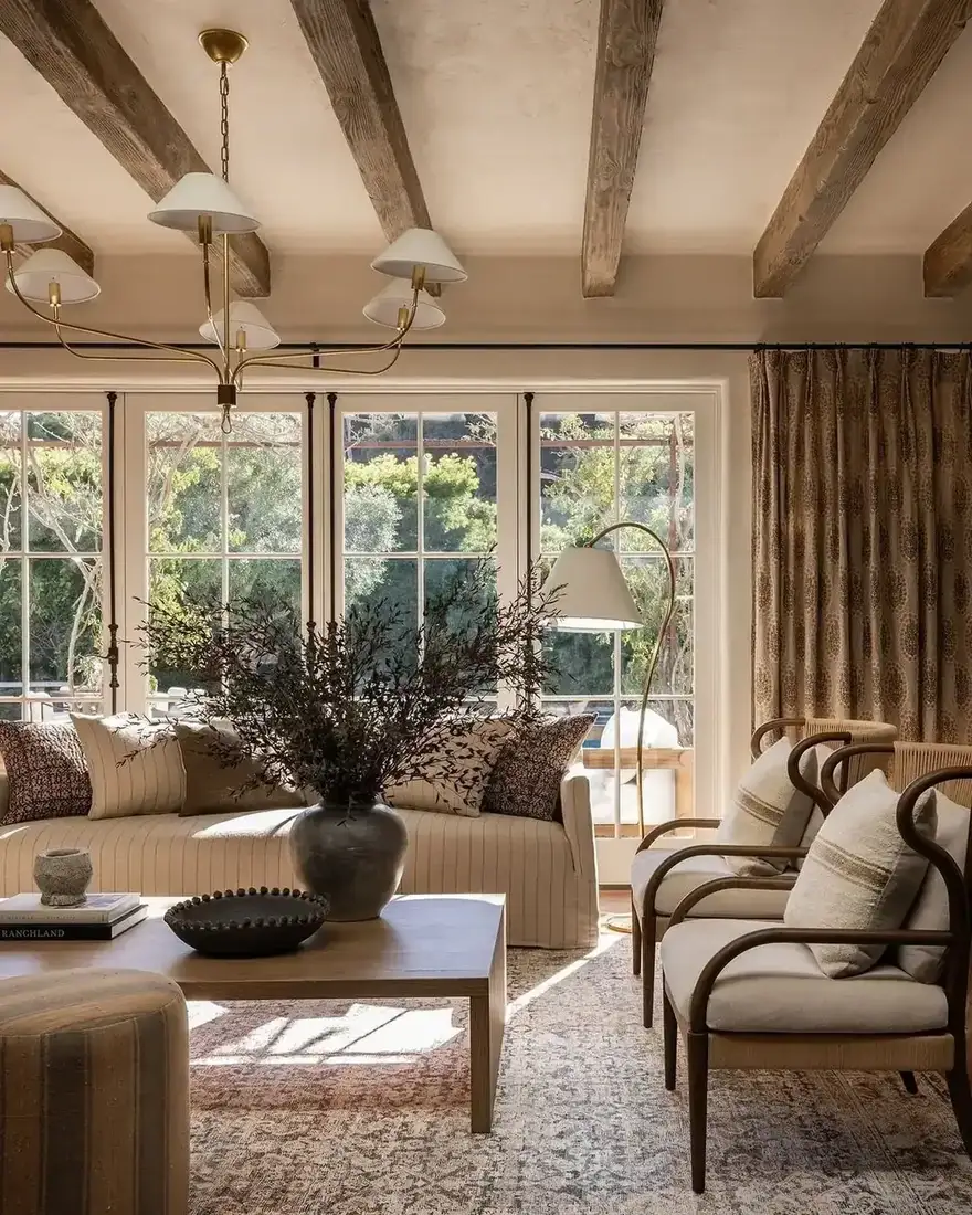Warm neutral living room with wood beams, vaulted ceiling and layered textiles