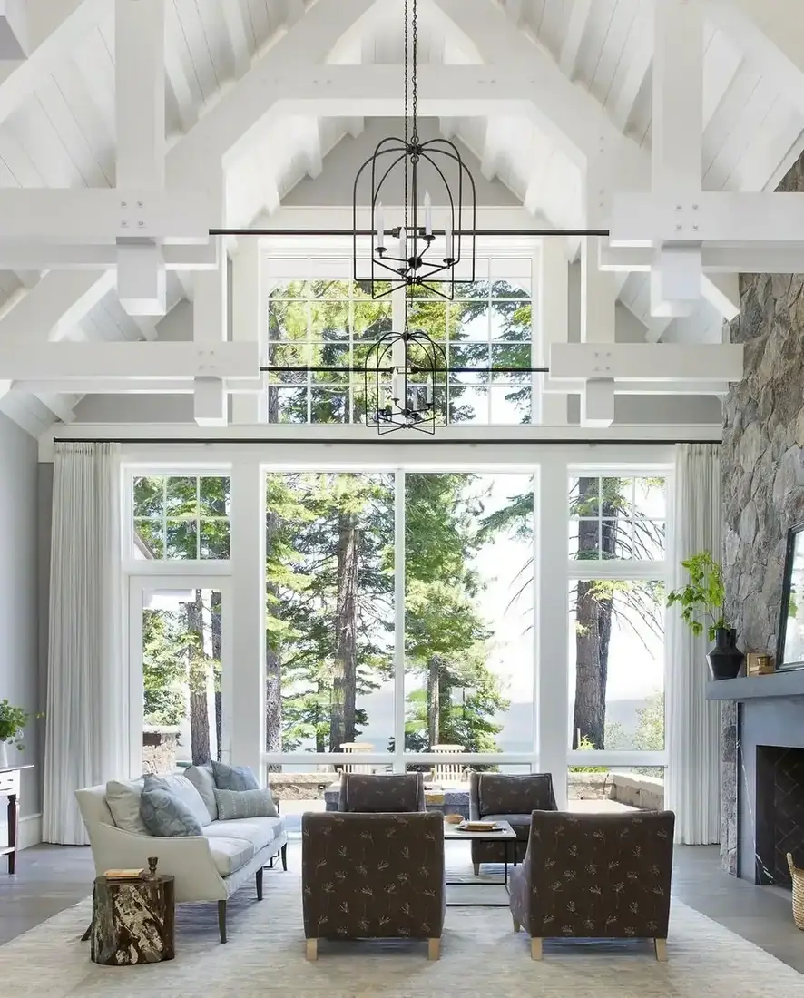 White vaulted ceiling living room with beams, fireplace and layered textiles