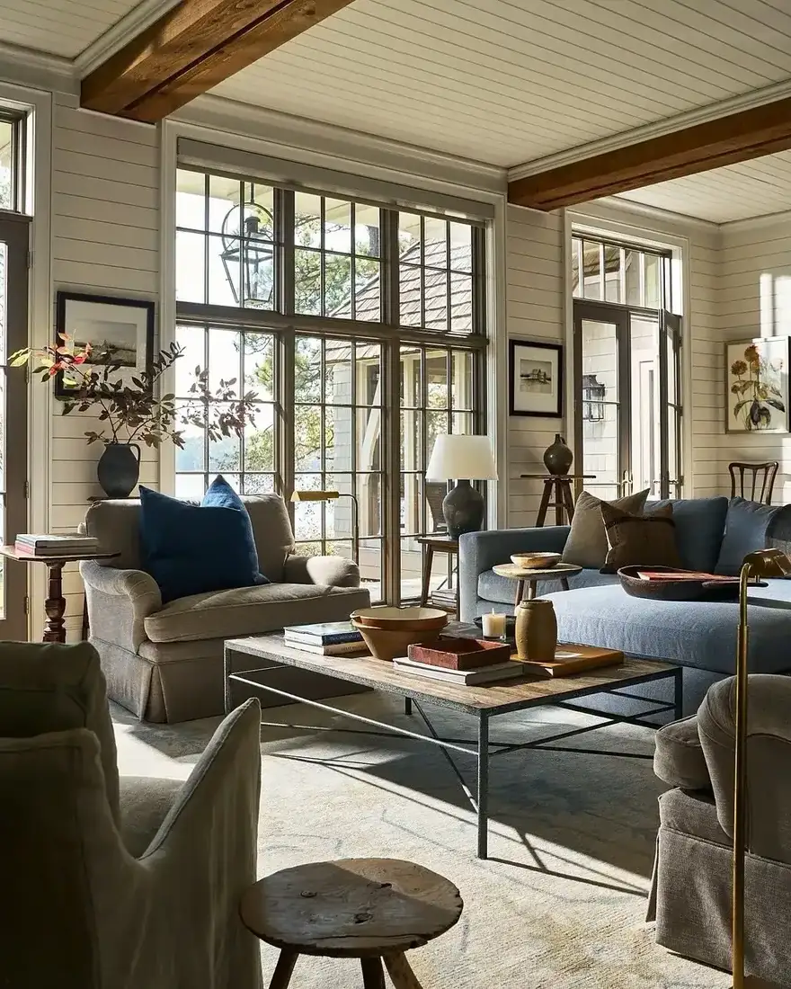 Lake house living room with steel windows, blue sofa and warm wood accents
