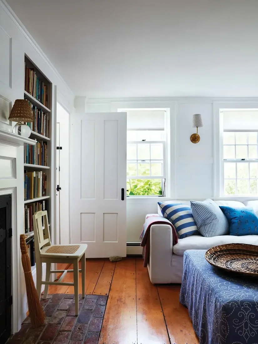 Coastal living room with white farmhouse sofa, blue pillows and soft light