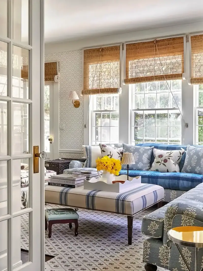 Blue floral sofa in a bright English cottage living room with layered textiles