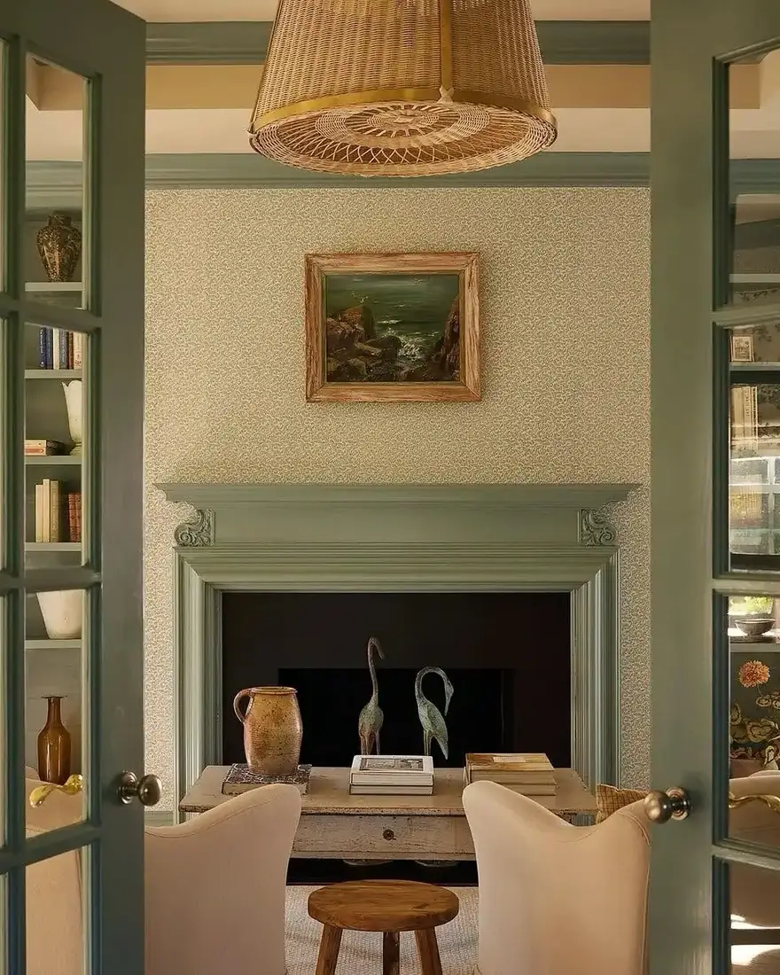 Sage green fireplace with built-in bookcases and mantel styled with three heights