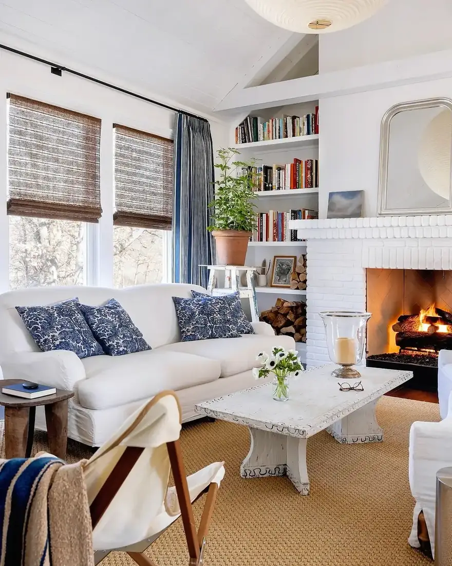 White living room with brick fireplace, blue pillows and sparse mantel styling