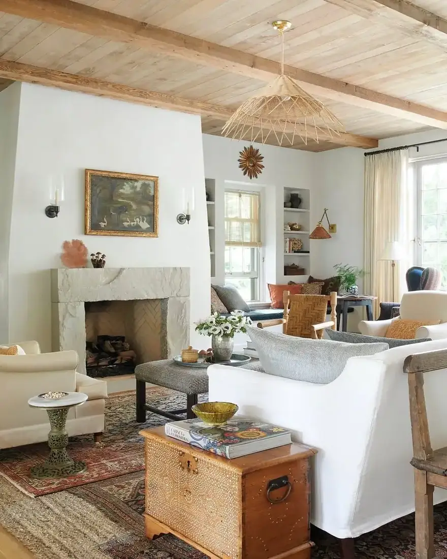 White living room with marble fireplace, wood ceiling and mantel styled with art
