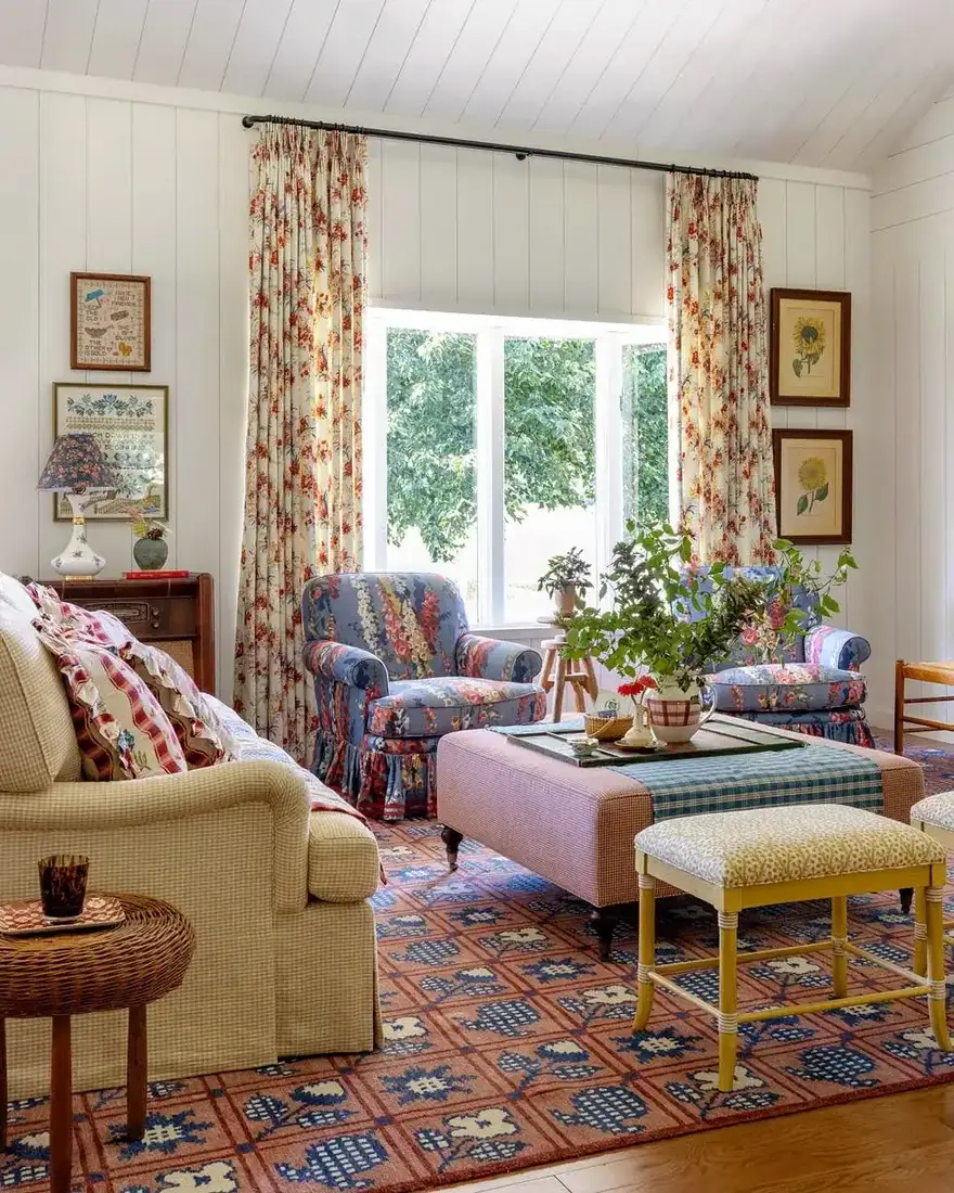 Floral chintz living room with pink ottoman, layered textiles and soft light