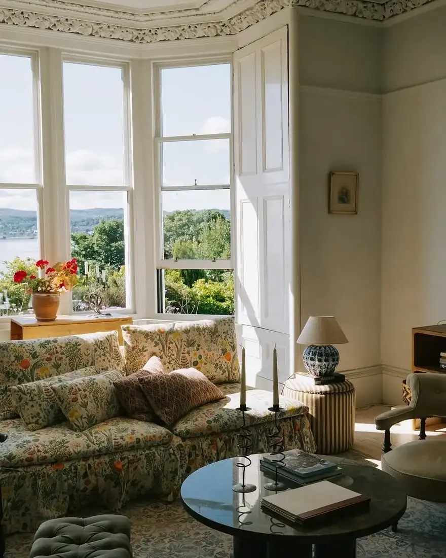 Floral sofa in a bay window with chintz textiles and natural light