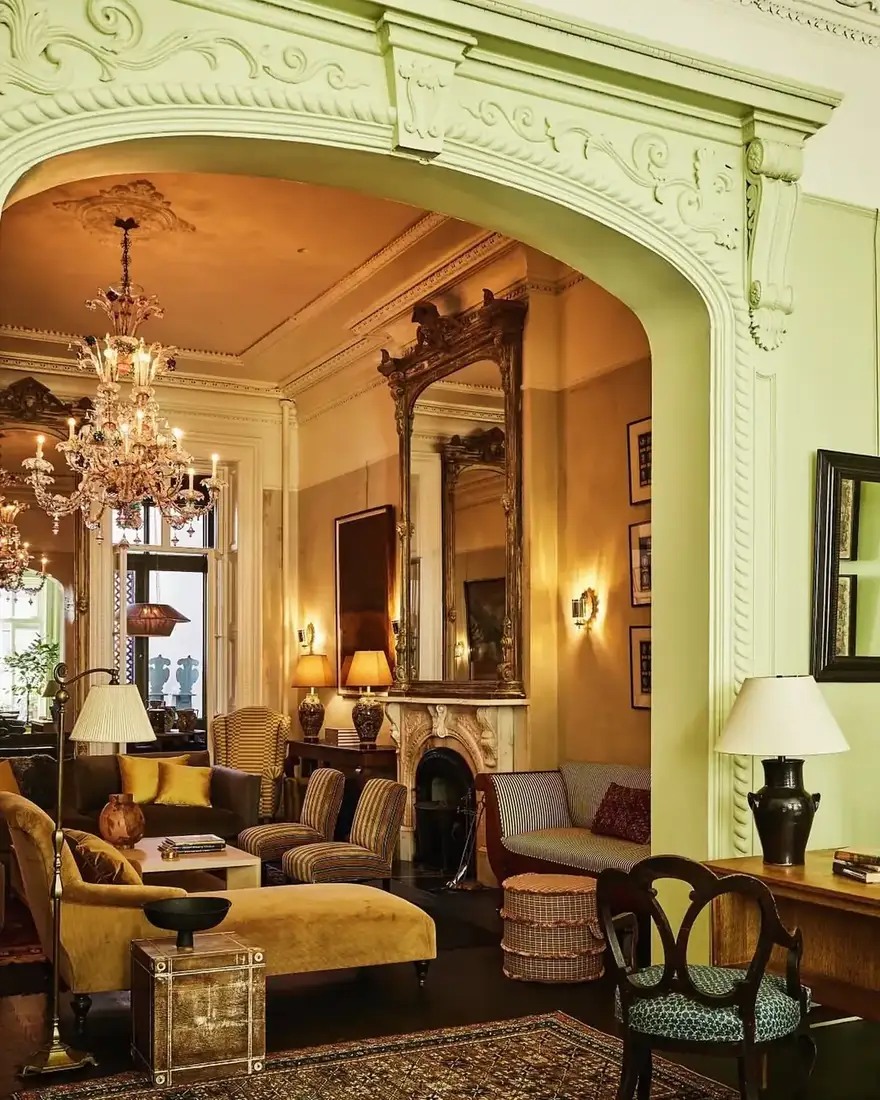 Ornate Victorian parlor with gold mirror, floral textiles and layered decor
