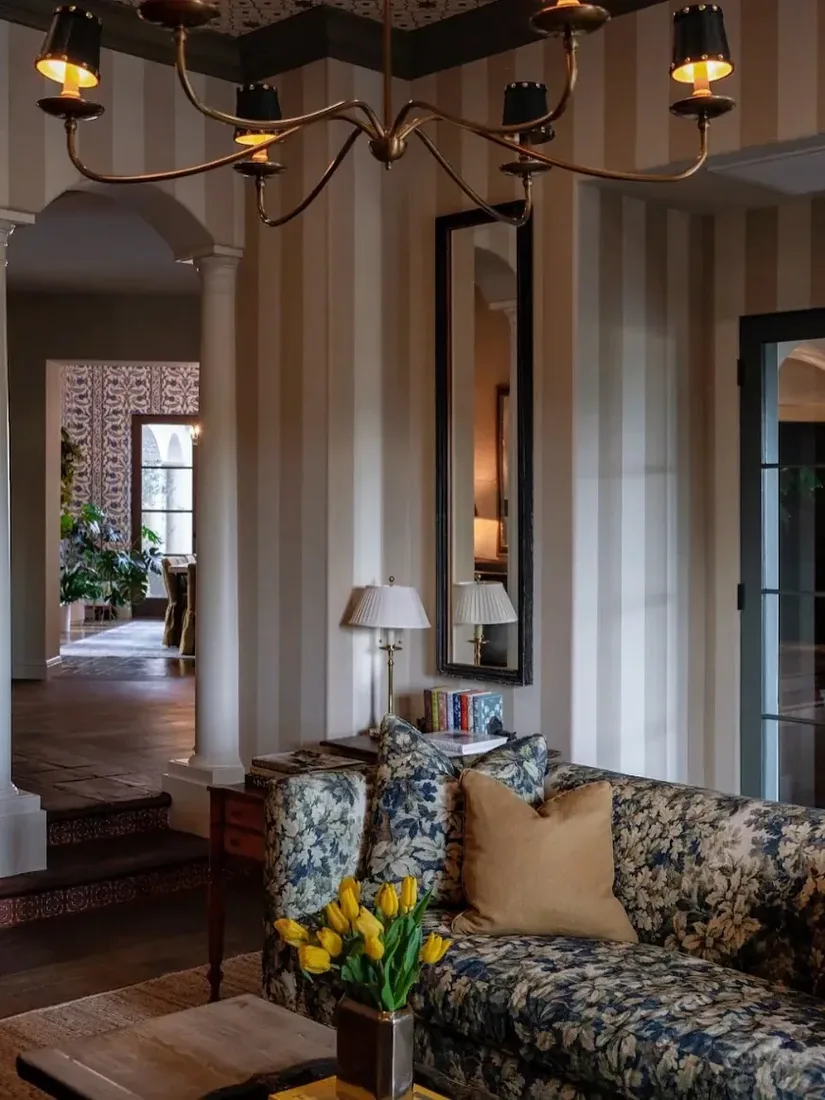 Traditional floral sofa with striped wallpaper, chintz textiles and warm light