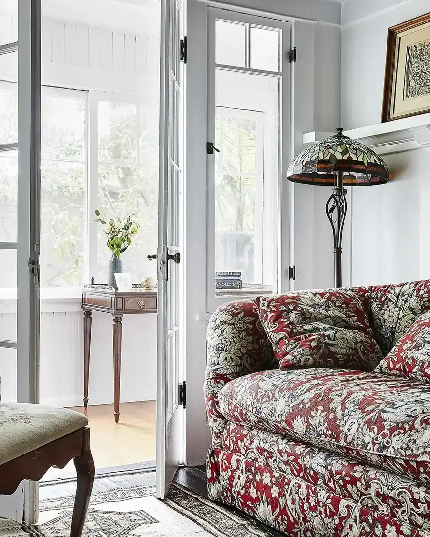 Vintage red floral sofa in a living room with layered textiles and warm light