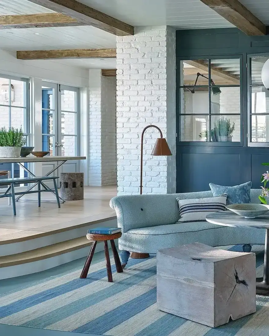 Coastal living room with whitewashed brick, blue stripes and warm wood accents