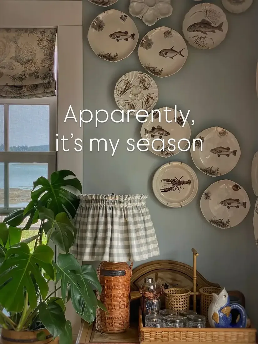 Vintage fish plate wall in a coastal living room with warm wood cabinet