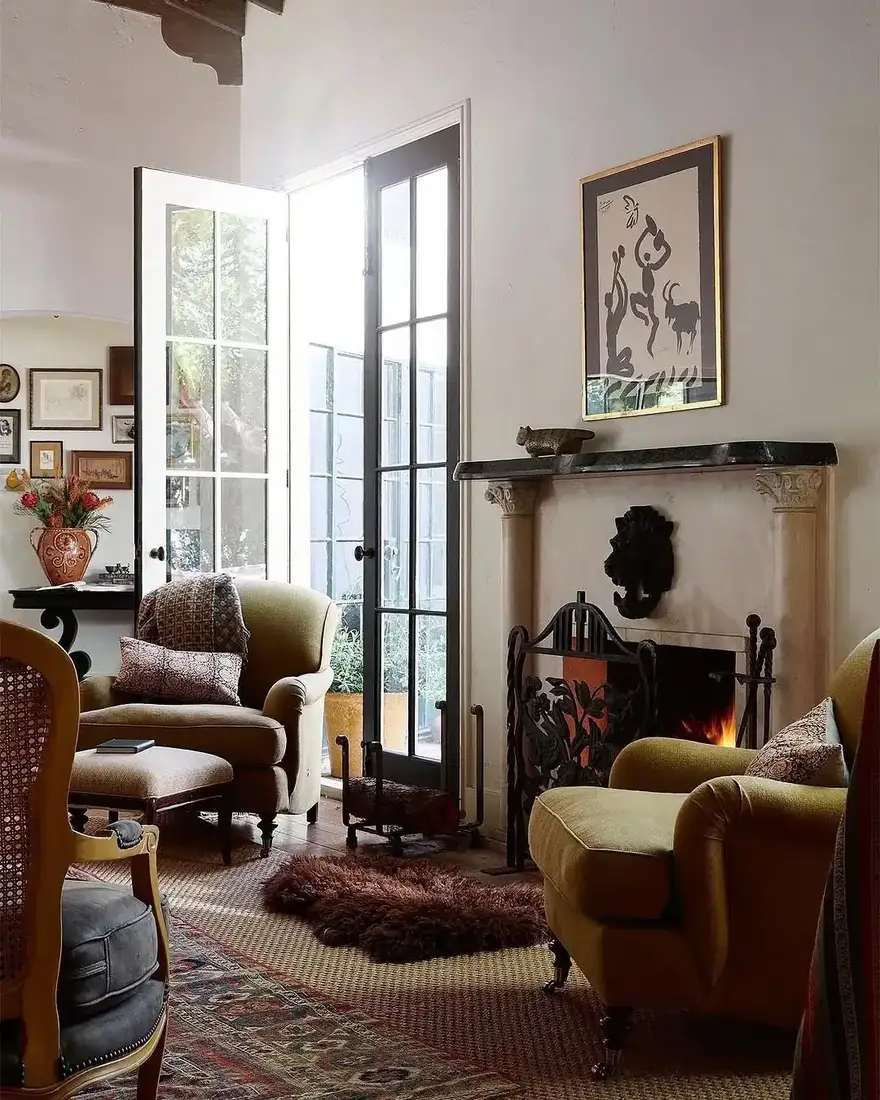 Antique French sitting room with gallery wall above a white marble fireplace