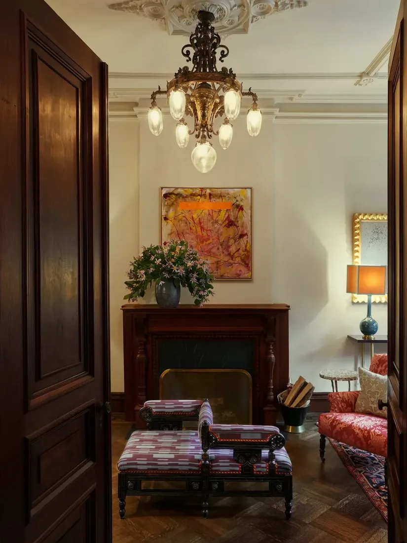 Marble fireplace with brass chandelier and minimal mantel styling in antique parlor