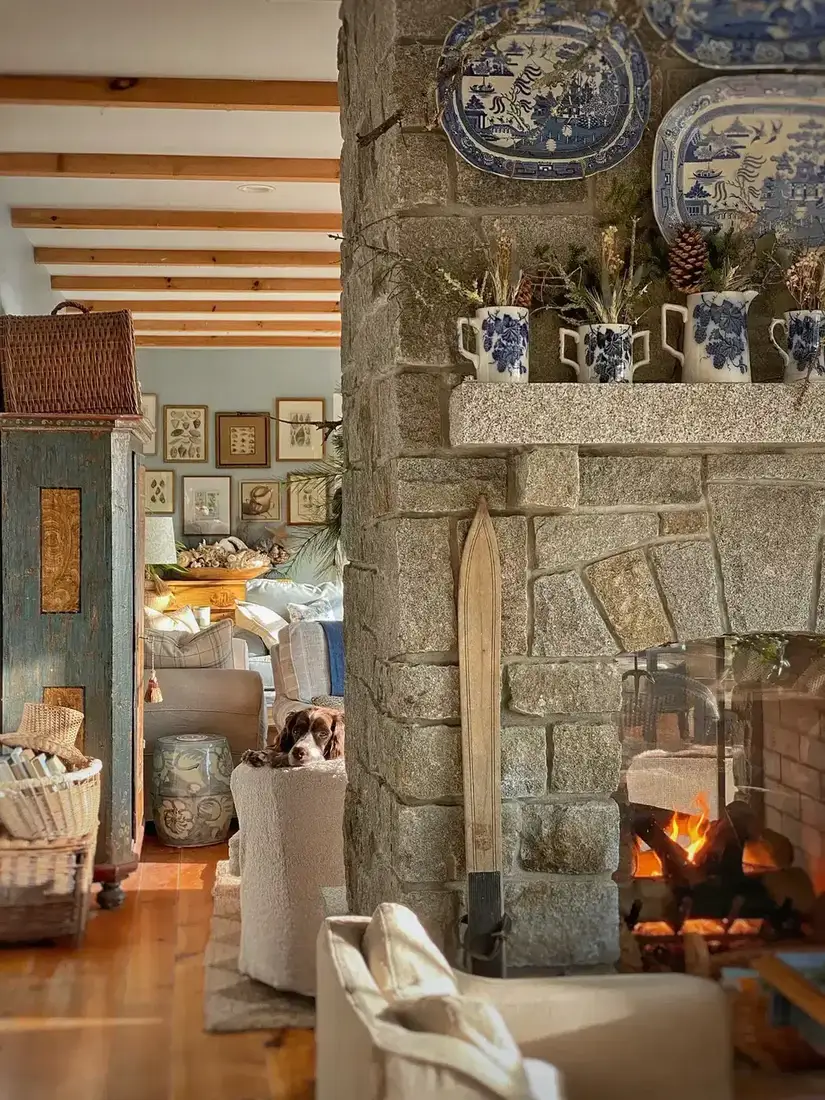 Cozy cottage stone fireplace with stacked logs and layered textiles