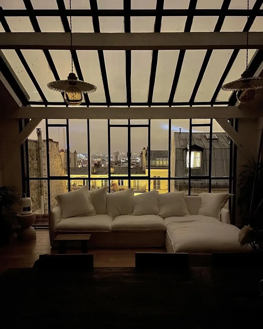 Industrial loft living room with steel windows, modern furnishings and layered textiles