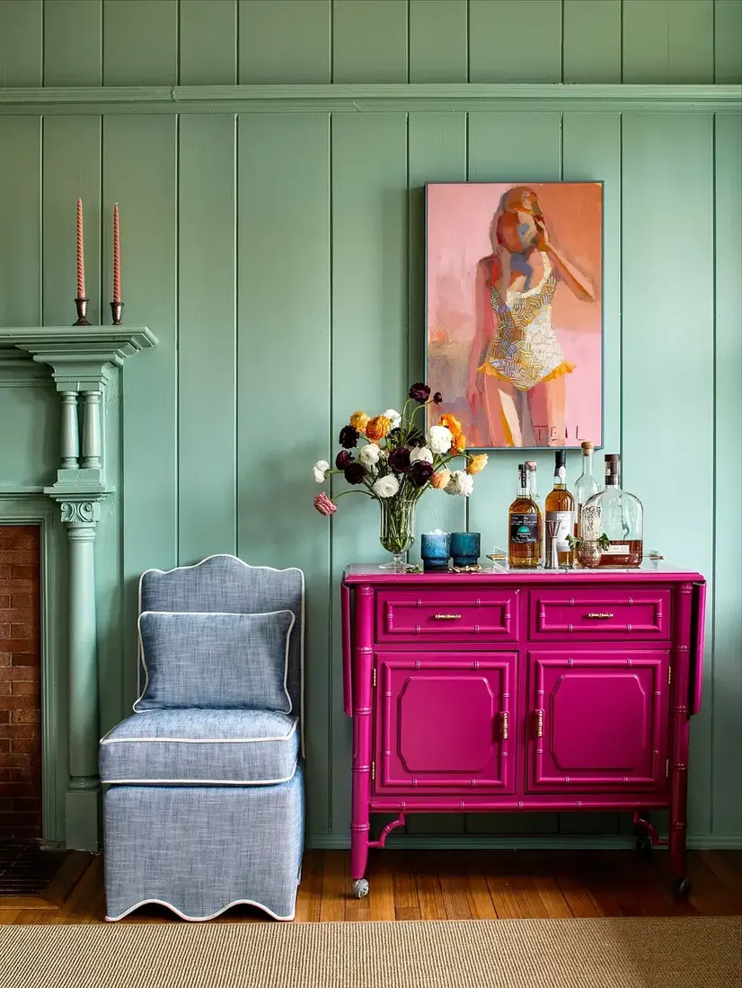 Pink bamboo cabinet with mint green walls in a cottage living room