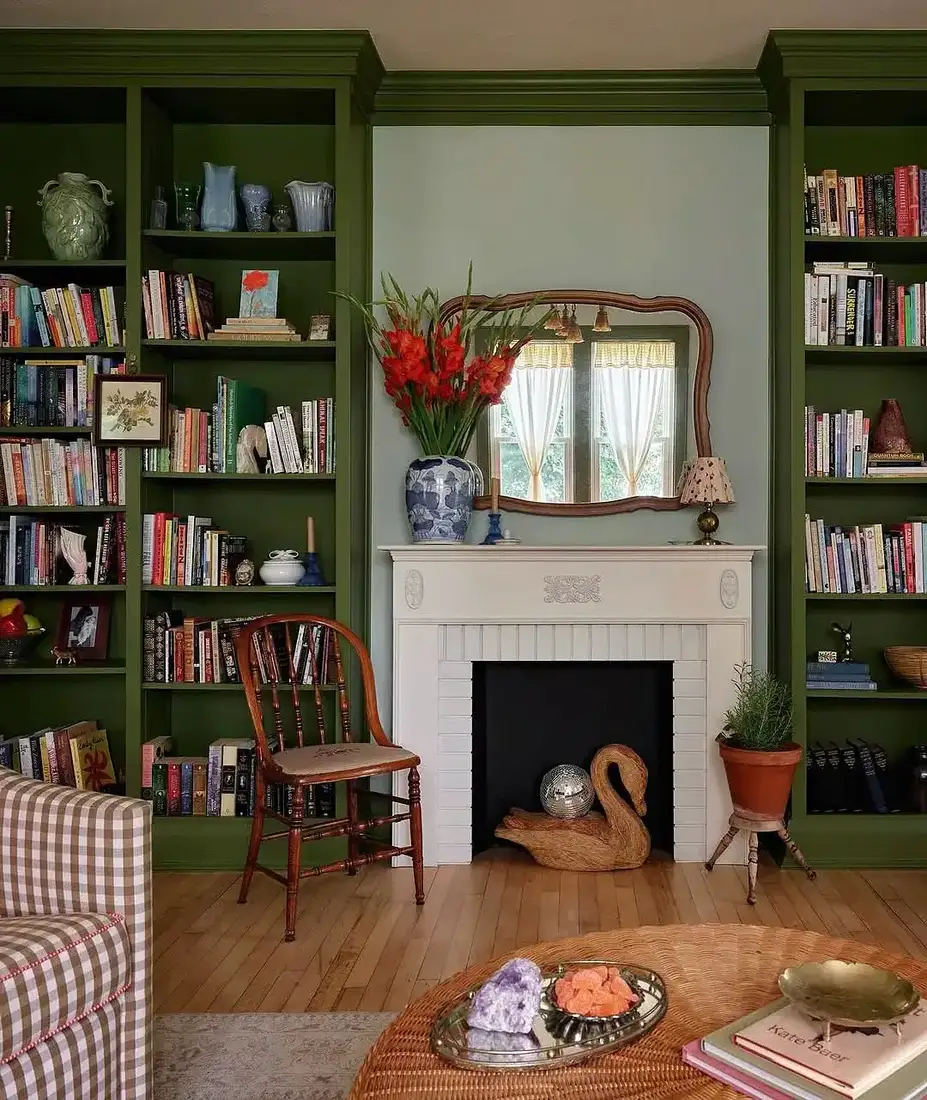 Living room with sage bookshelves flanking a stone fireplace with wooden mantel