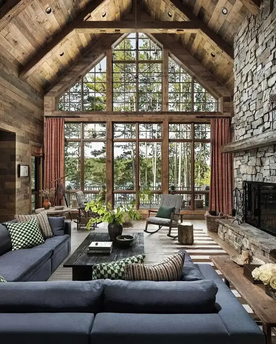 A-frame living room with tall stone fireplace and timber beams as the anchor